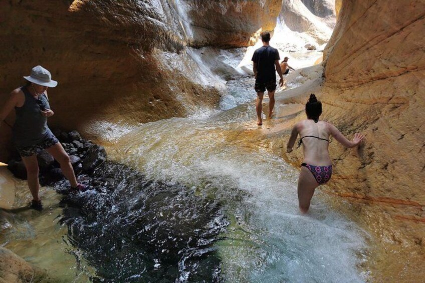 People wading through a narrow water channel in a canyon. 2