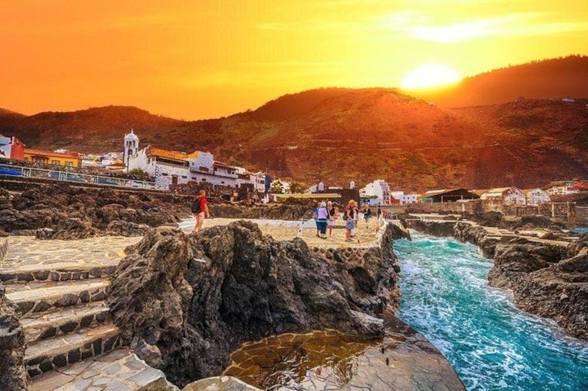 Une ville côtière avec un littoral rocheux, une rivière et un coucher de soleil. 1