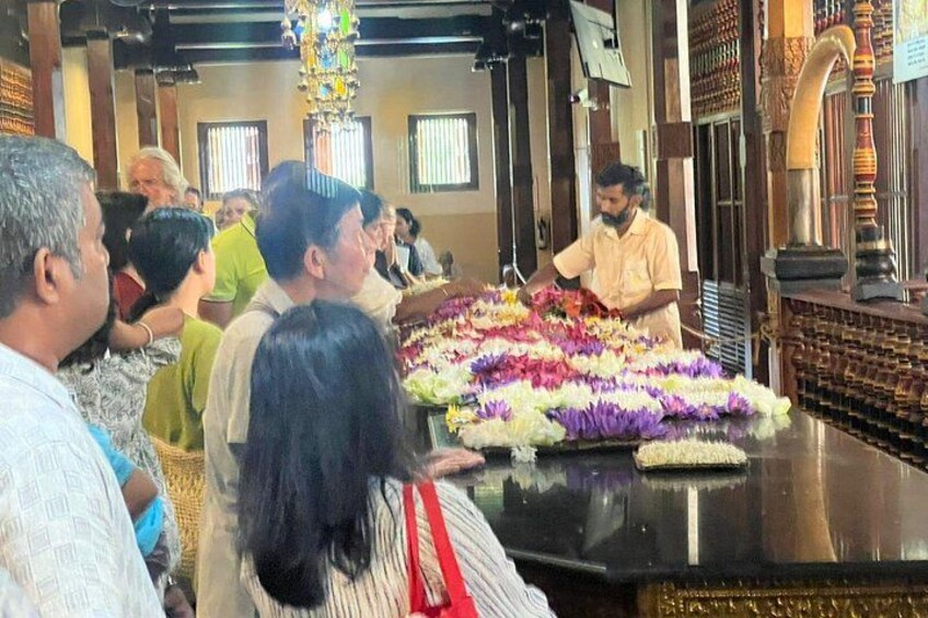A group of people in a temple, with a man arranging flowers on a table. 3