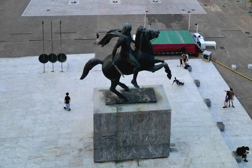 A statue of a horse and rider on a pedestal in an open plaza with people around. 1