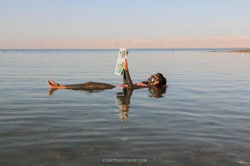 A person floating on water with a dog, holding a book. 2