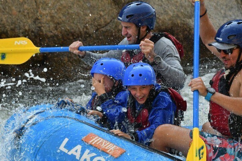 A group of people in a blue inflatable raft labeled 'Lakeside' paddling through water. 3