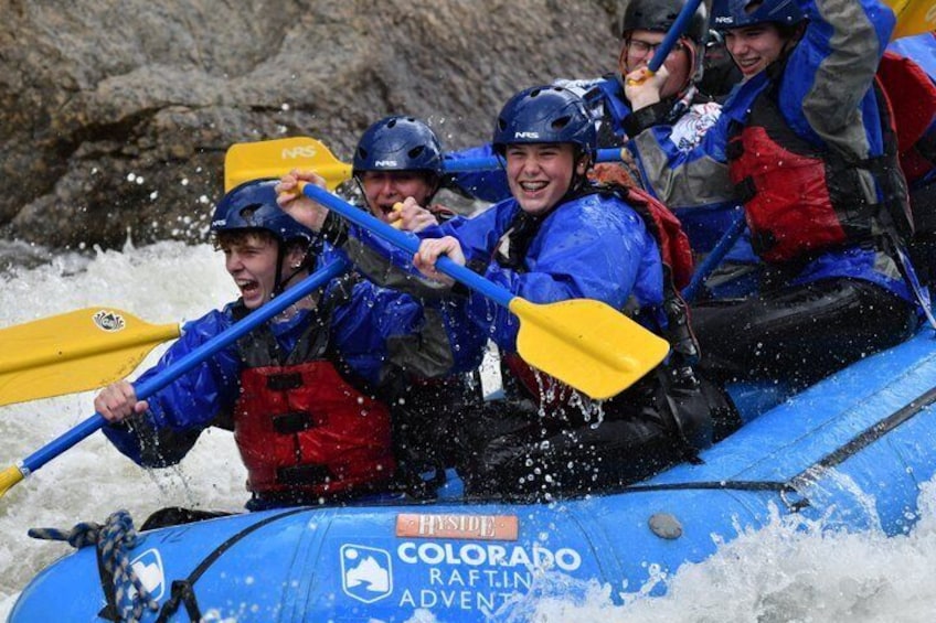 A group of people in a blue raft with yellow paddles, navigating through a river. 4