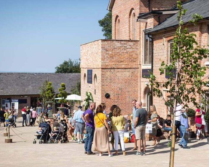 A group of people standing and walking in a courtyard with a brick building in the background. 5