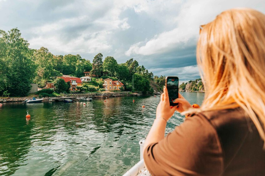 A person taking a photo of a river with houses and trees on the banks. 5