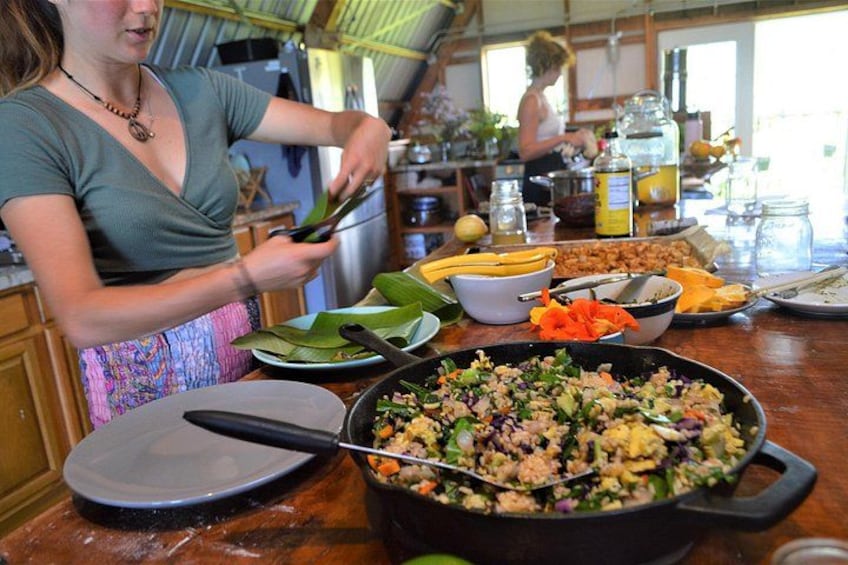A person cooking with a pan on a wooden countertop, surrounded by various ingredients and kitchen utensils. 5