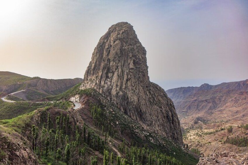 A rugged mountain peak with a winding road leading up. 1
