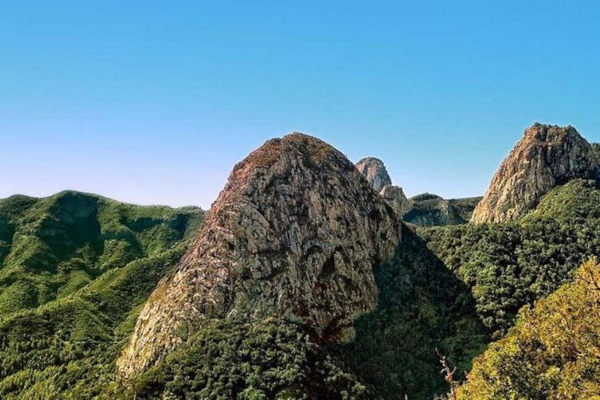 A mountainous landscape with prominent rock formations and dense green vegetation. 2