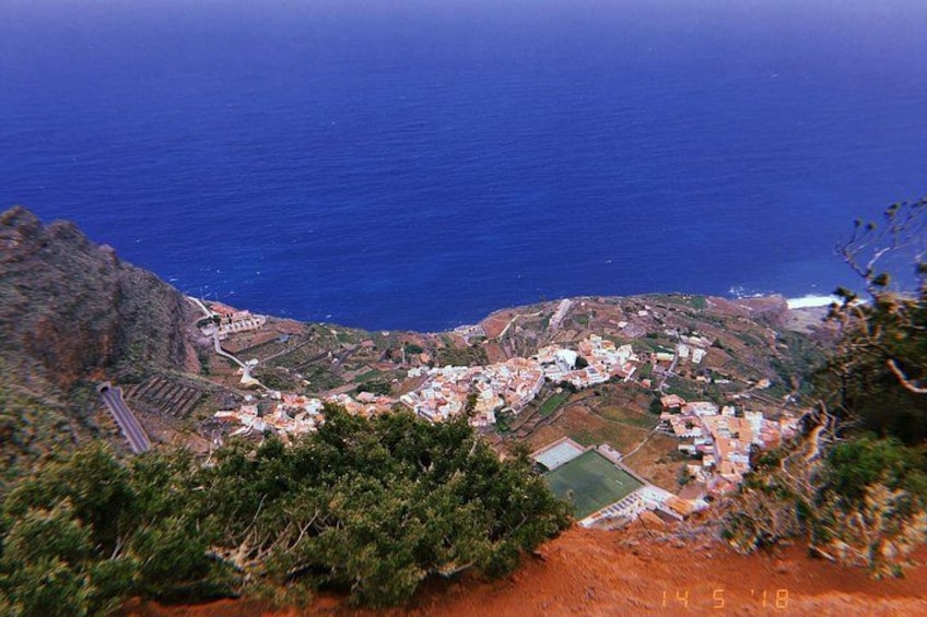 Un village côtier avec des bâtiments, une route et une chaîne de montagnes en arrière-plan. 2