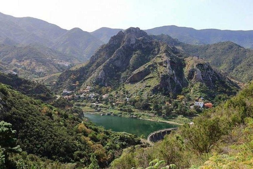 A mountainous landscape with a lake, a bridge, and scattered buildings. 4