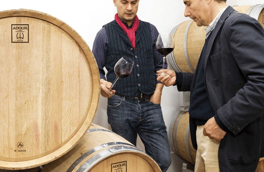 Two people examining wine barrels in a cellar. 2