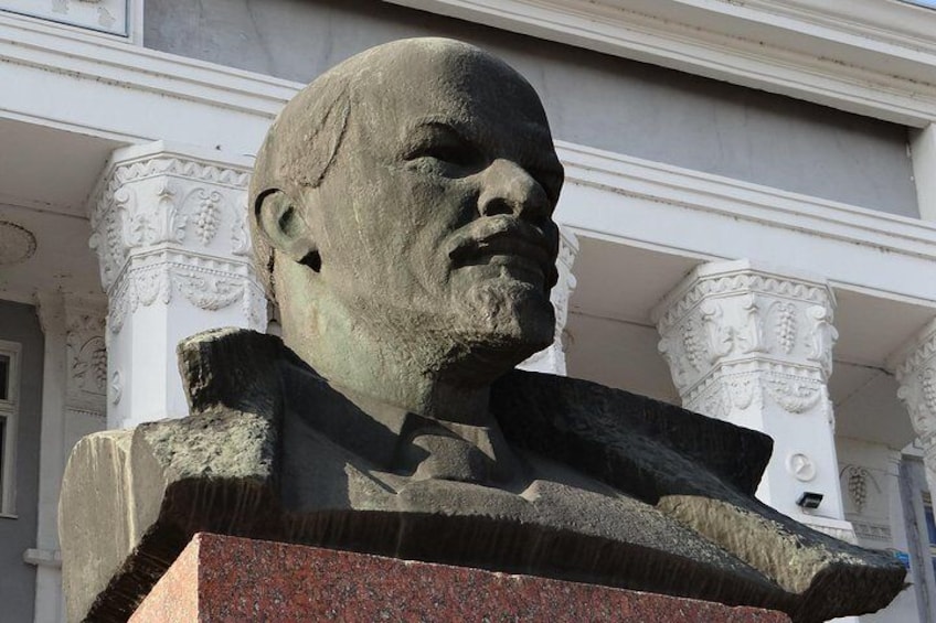 A stone bust sculpture on a pedestal in front of a building with ornate columns. 4