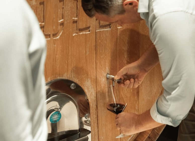 A person pouring wine from a bottle into a glass. 3