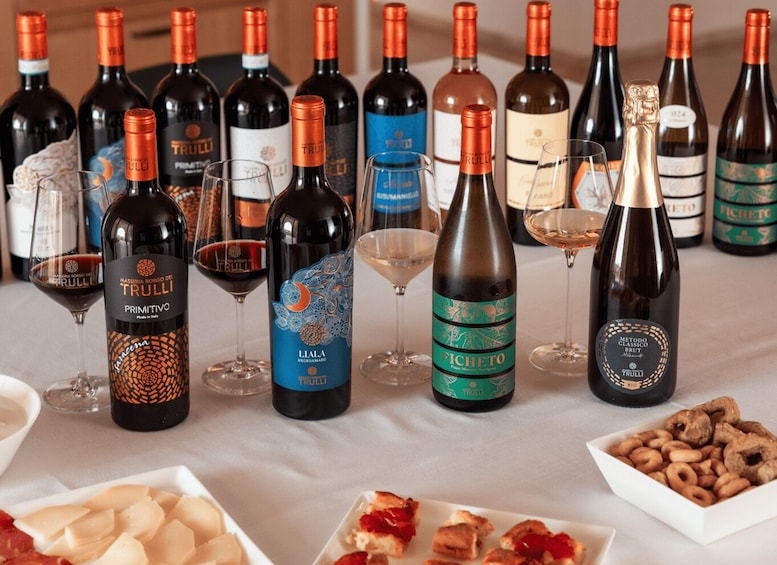 A table with various wine bottles and glasses, some food items, and a decorative item. 2