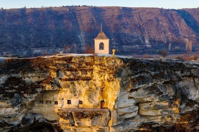 Una chiesa a picco sulla scogliera, con un paesaggio roccioso sullo sfondo. 1
