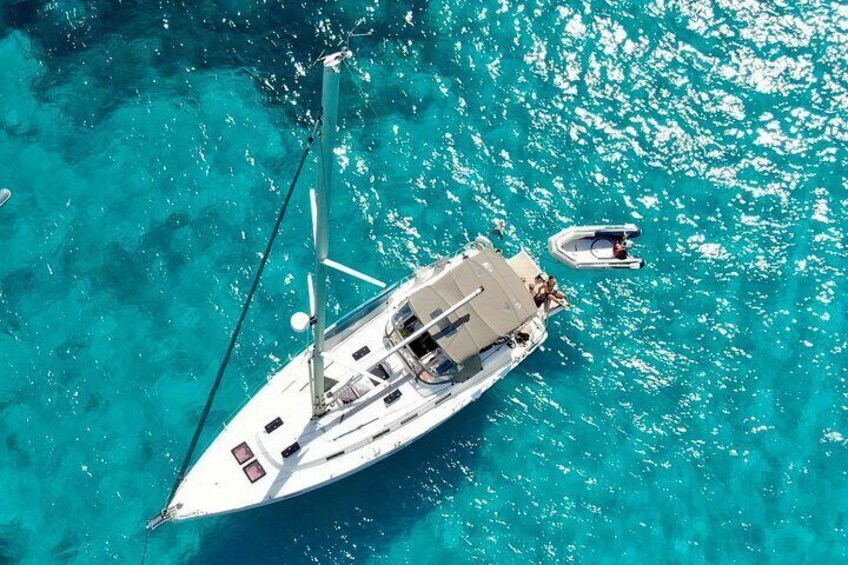 A sailboat with a cabin and a smaller boat nearby in turquoise waters. 2