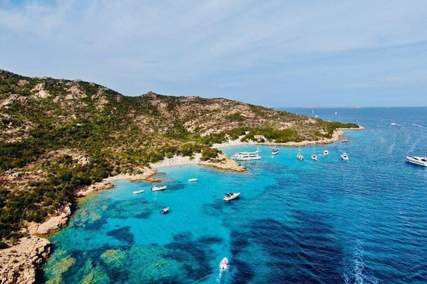 Un paysage côtier avec des bateaux, une eau d’un bleu limpide et un relief vallonné. 3