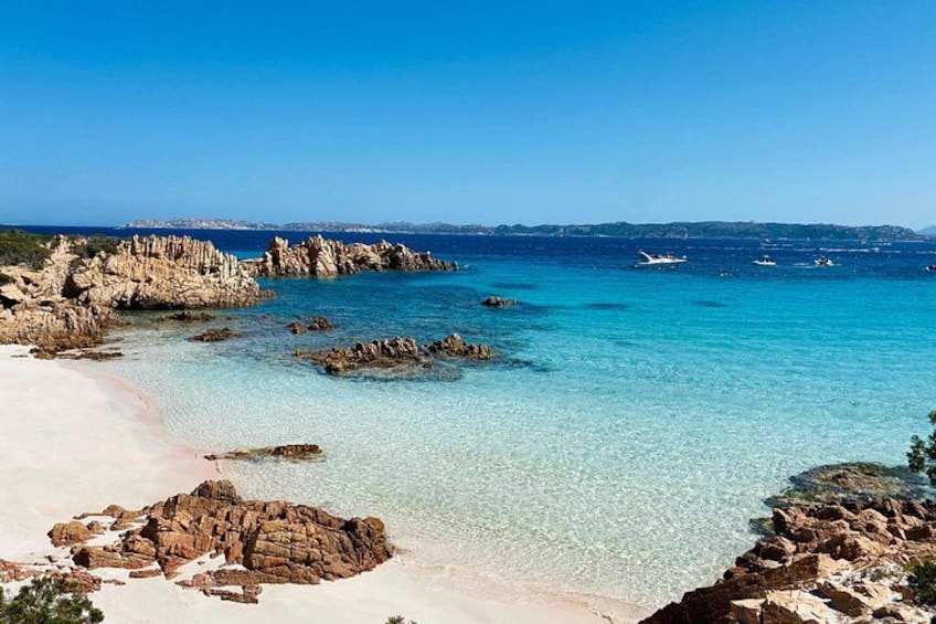 Un paysage côtier caractérisé par une eau turquoise cristalline, des formations rocheuses et une plage de sable. 1