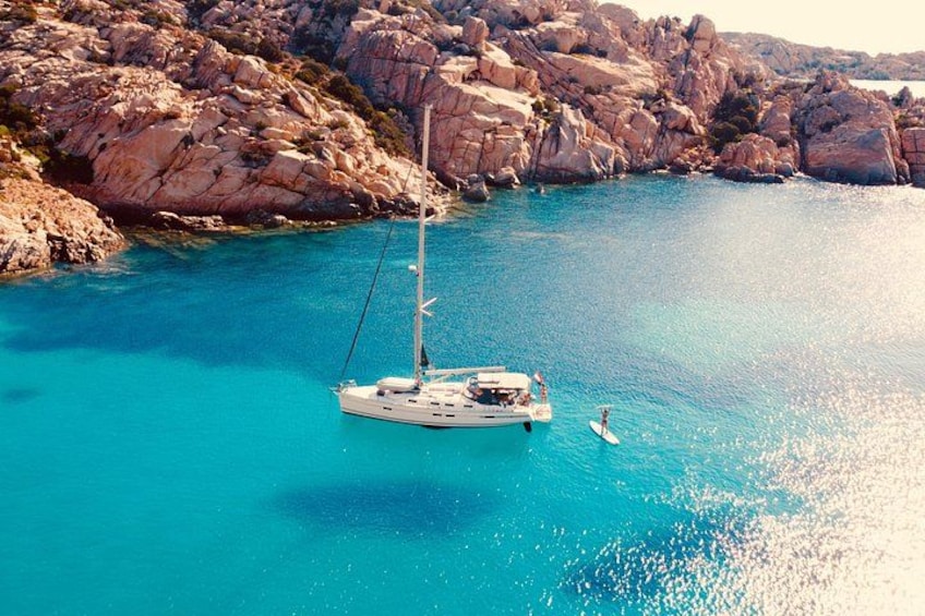 Un velero anclado cerca de la costa rocosa con agua turquesa cristalina. 2
