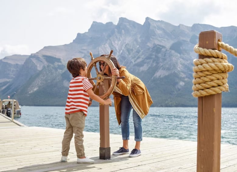 Un enfant et un adulte sur un quai en bois, interagissant avec un gouvernail de bateau. 4