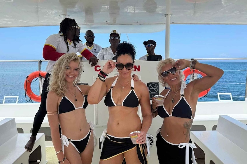 Three women in bikinis on a boat with the ocean in the background. 1