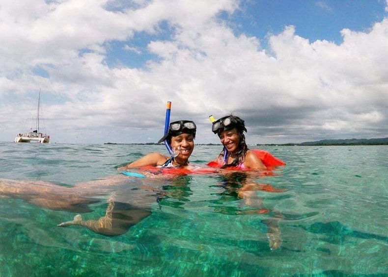 Two people snorkeling in clear water with a boat in the background. 2