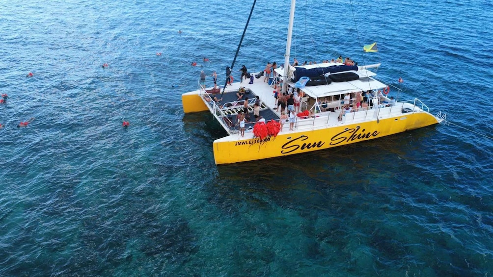A yellow boat named 'Sun Shine' with people on board and swimmers in the water. 3