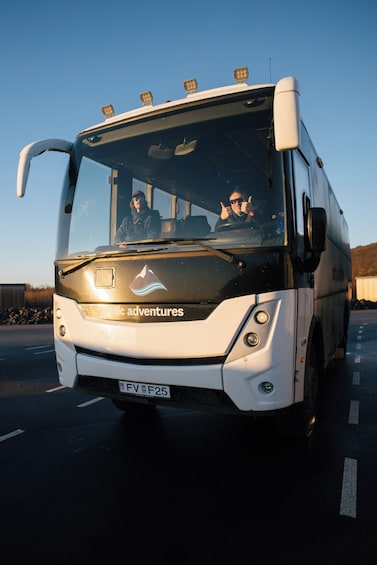 A white bus with the text 'arctic adventures' on the front, driving on a road. 5