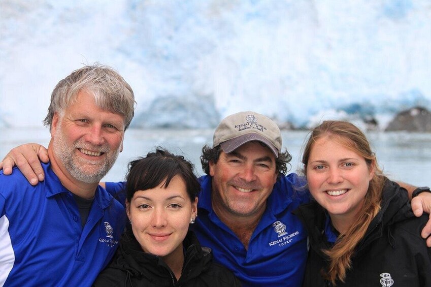Four people wearing blue shirts with logos, standing in front of a snowy landscape with ice formations. 5
