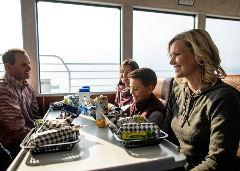 A group of people seated at a table with food and drinks on a ship. 3