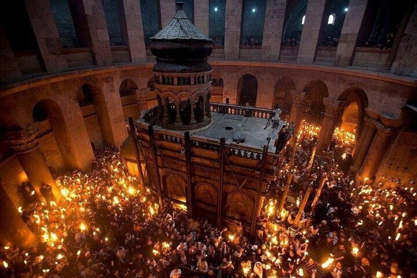 A large crowd gathered around a central structure with a dome, surrounded by arches. 1