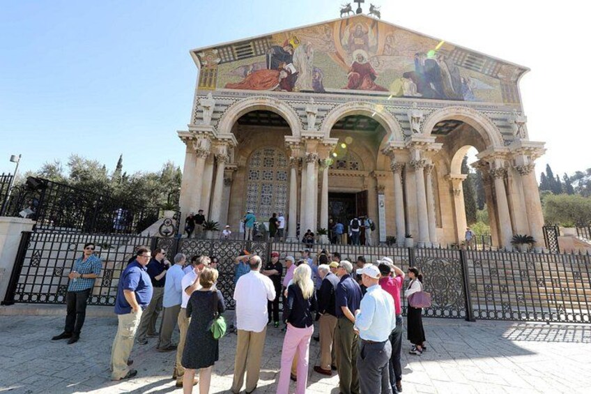 A group of people gathered in front of a building with classical architecture and a detailed mosaic. 3