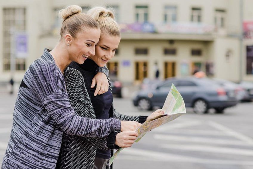 Dos personas revisan un mapa al aire libre, con edificios y coches al fondo. 3