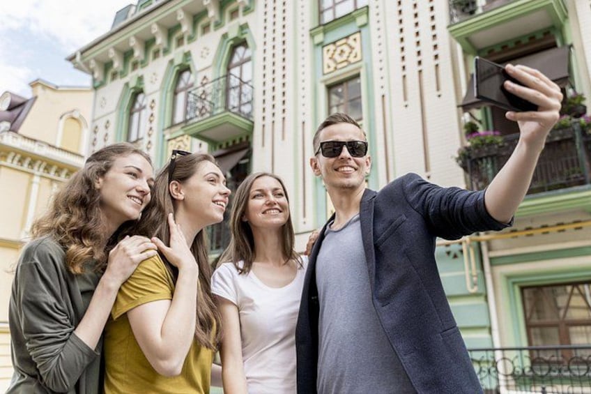A group of people taking a selfie in front of a building with ornate architecture. 2