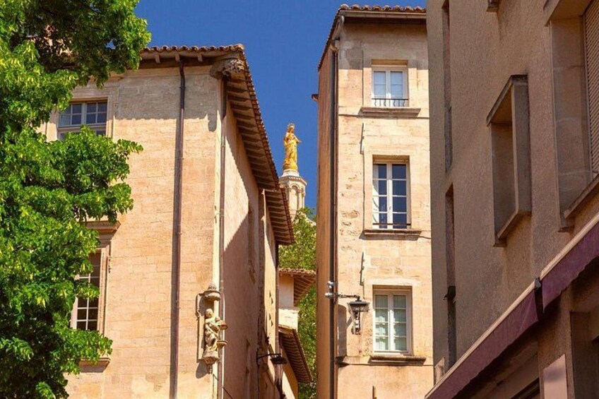 Una calle estrecha con edificios, una estatua y un árbol. 3