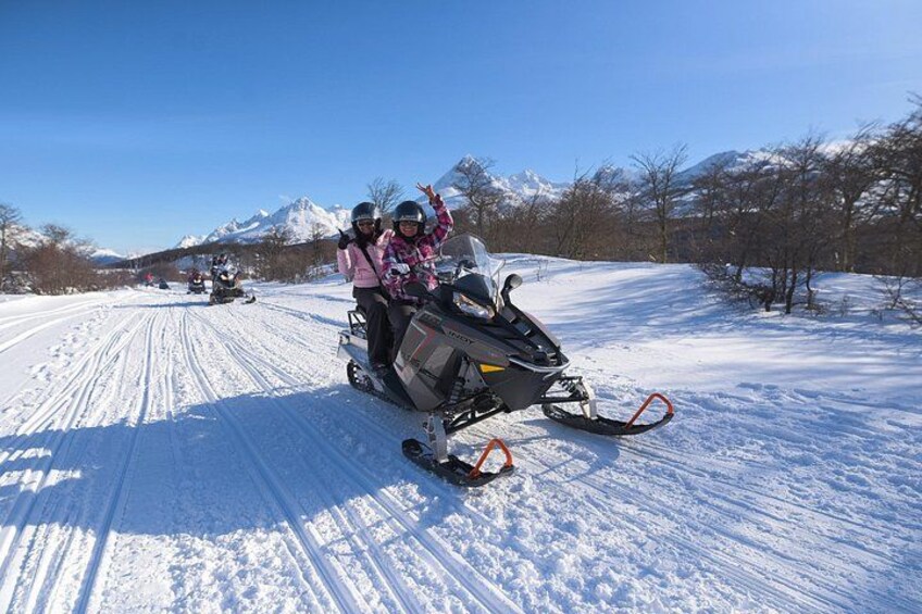 Un vehículo para la nieve circulando por un sendero cubierto de nieve, con montañas al fondo. 5