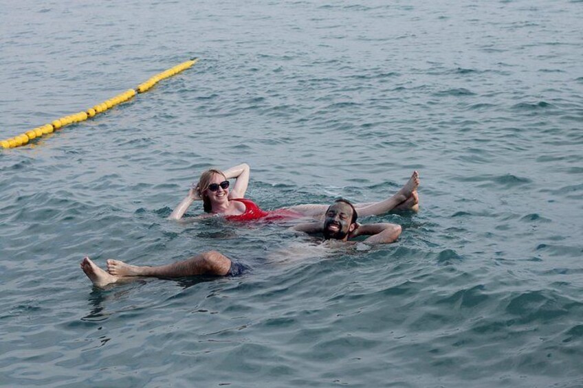 Deux personnes flottent sur l’eau, avec une barrière de sécurité jaune flottante en arrière-plan. 4