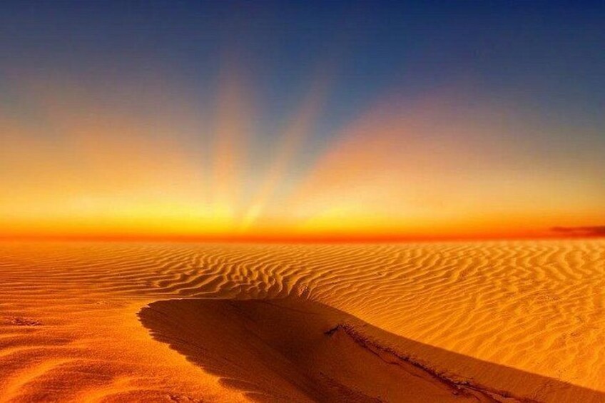 A desert landscape with rippled sand dunes under a sunset sky. 5