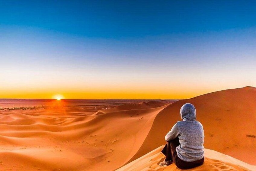 A person sitting on a sand dune at sunset. 4