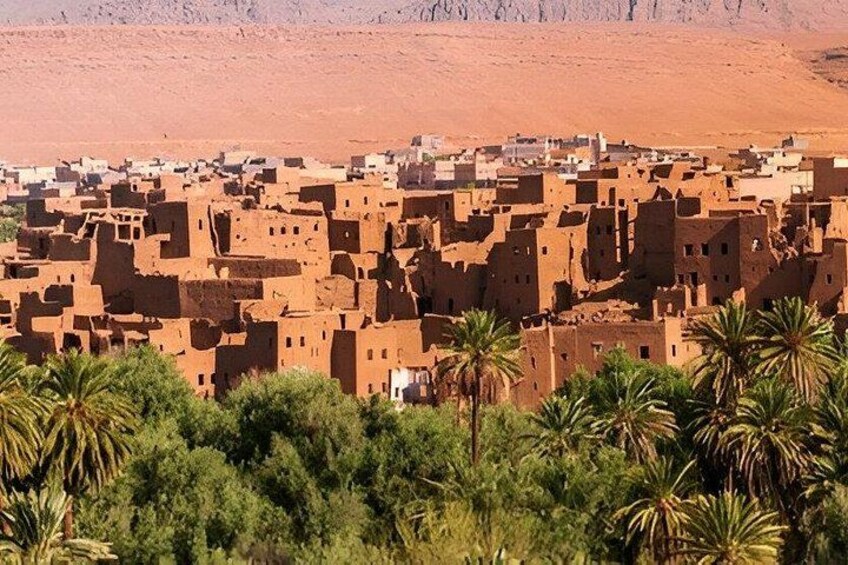 A desert landscape with a village of adobe buildings and palm trees. 3