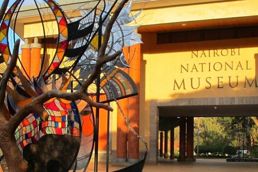 The Nairobi National Museum entrance with a colorful sculpture and a sign. 1