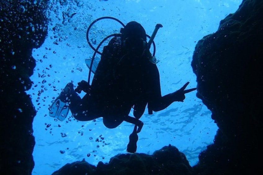 A diver in a cave with visible bubbles and rocky formations. 2
