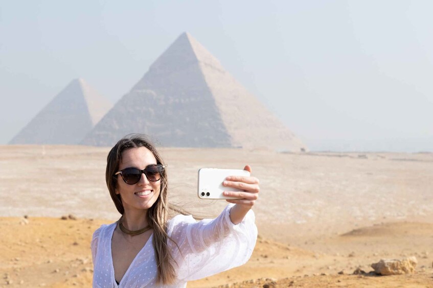 A person taking a selfie with the pyramids in the background. 1