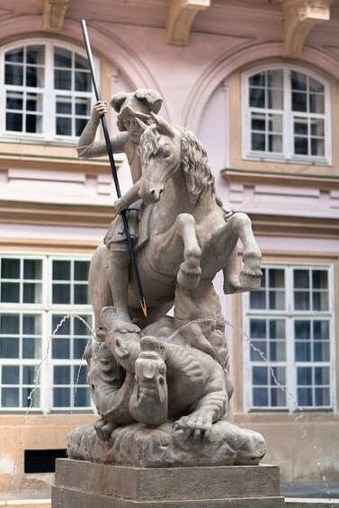 Une statue de pierre représentant un homme à cheval, avec un lion attaquant un plus petit animal en contrebas. 4