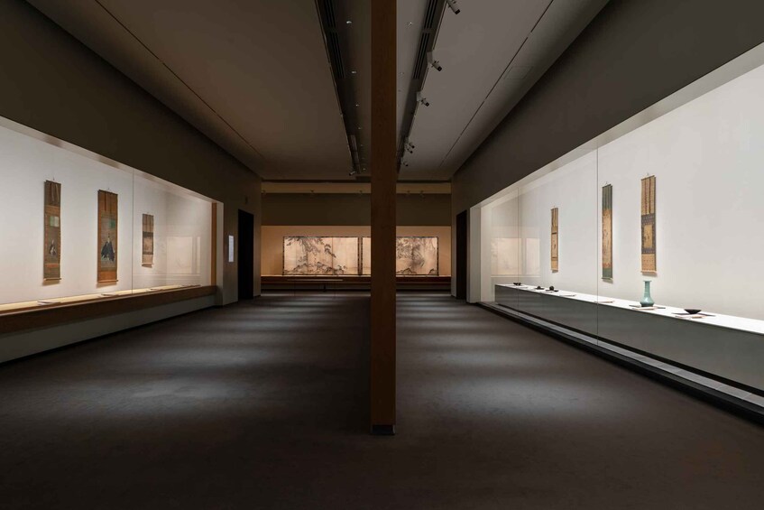 An art gallery with paintings on the walls and a large central pillar. 5