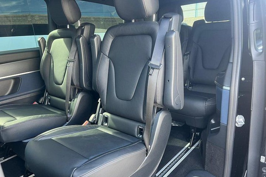 A car interior with black leather seats and seat belts. 2