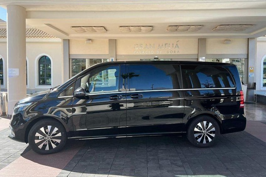 A black van parked in front of a building with a sign that reads 'GRAN MELIA PALACIO DE ISORA.' 1