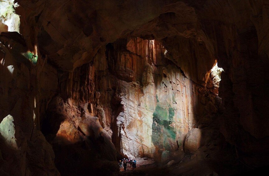 A cave with stalactites and stalagmites, illuminated by natural light. 3