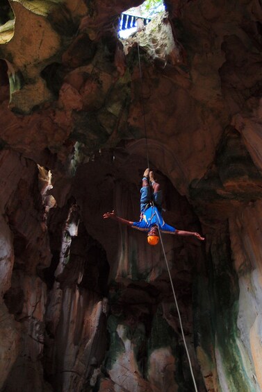 A person suspended in mid-air by a rope in a cave. 4
