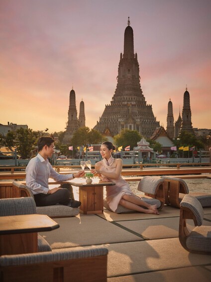 A couple sitting at a table outdoors with a temple in the background. 1